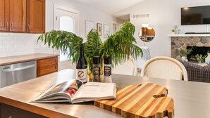 Una cocina moderna con armarios de madera, chimenea de piedra y comedor con mobiliario de mimbre.