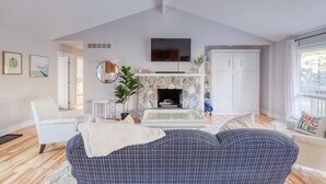 Una sala de estar con chimenea, televisor y un ventanal grande.