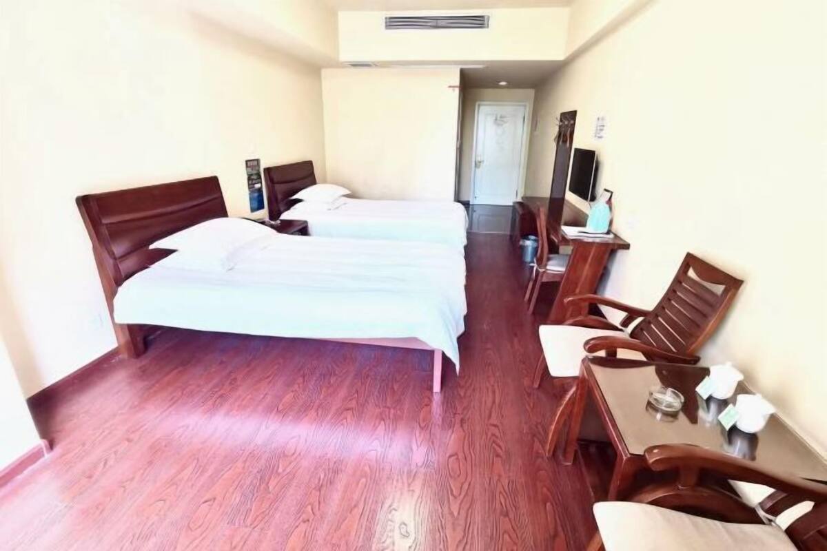 A hotel room with two beds, a wooden desk, and a chair.
