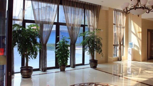 A spacious lobby with large windows, potted plants, and a chandelier. - Puyuan Qihonglou Hotel (Tongxiang)