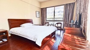 A hotel room with a large bed, a desk, a chair, a small table, a window with curtains, and a balcony. - Puyuan Qihonglou Hotel (Tongxiang)