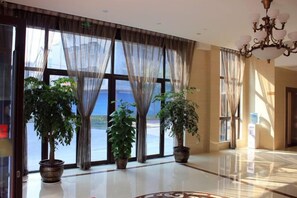 Un vestíbulo amplio con ventanas grandes, plantas en macetas y un candelabro.