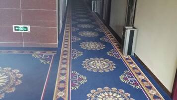 Un pasillo con alfombra estampada y una señal de indicaciones.