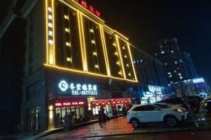 Un edificio con letreros iluminados, una entrada visible y un coche estacionado.