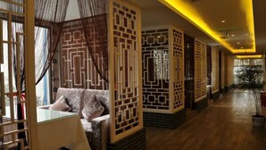 A hotel corridor with traditional decor, including patterned screens and a sofa with cushions. - Chongzhou Lanfeng Hotel (Chongzhou)