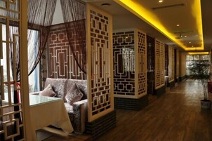 Un pasillo de hotel con decoración tradicional, que incluye paneles decorativos y un sofá con cojines.