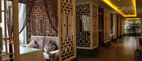 Habitación de hotel con suelo de madera, un sofá, una cama y un separador con diseños geométricos.