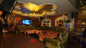 A luxurious lounge area with a large, ornate sofa, a wooden coffee table, and a television screen. - Chongzhou Lanfeng Hotel (Chongzhou)