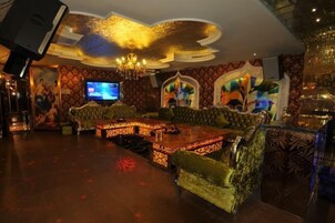Un espacio de descanso lujoso con un sofá grande y ornamentado, una mesa de centro de madera y una pantalla de televisión.