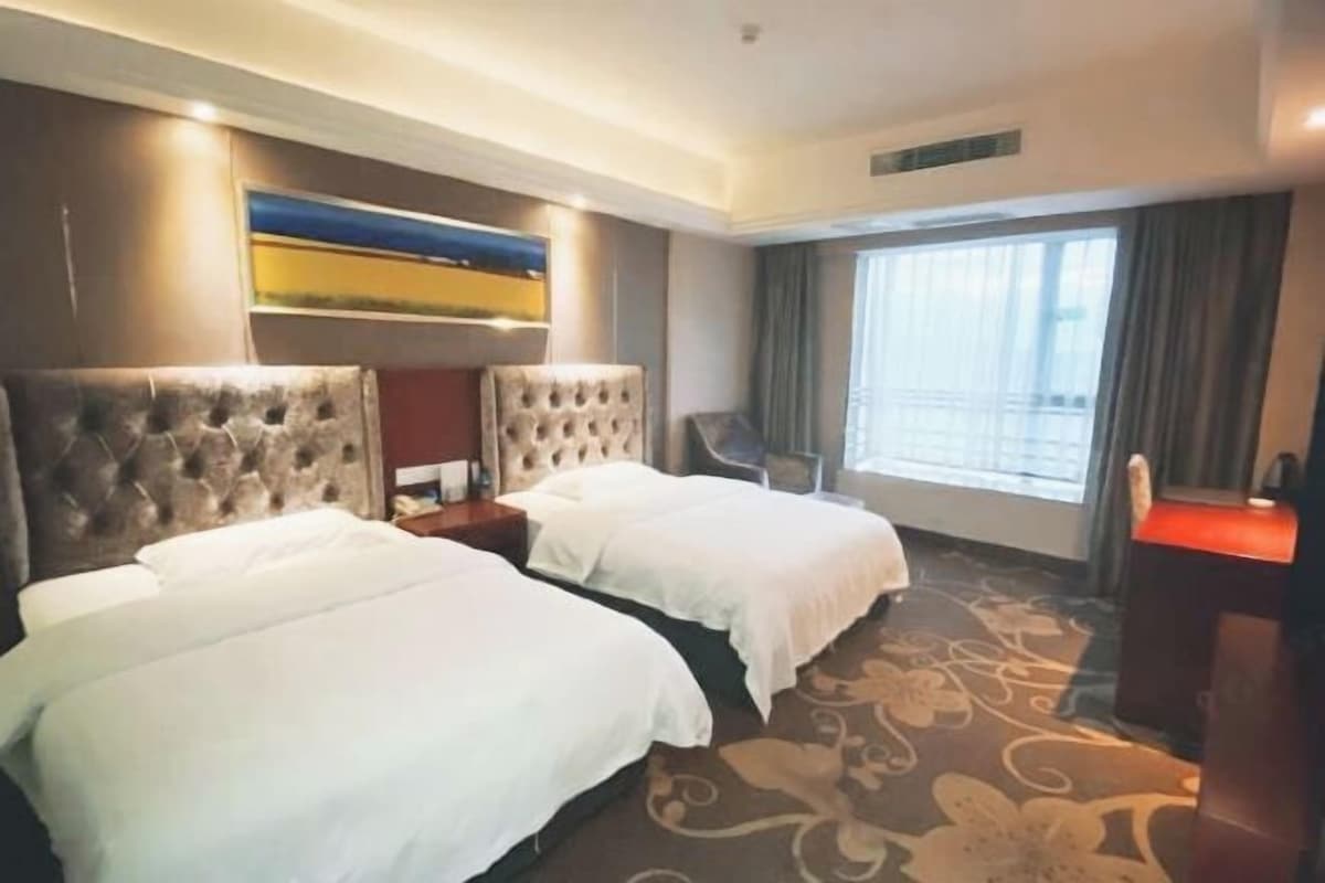 A hotel room with two beds, a large window, and a flat-screen TV.