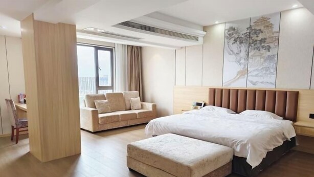 A modern hotel room with a large bed, a sofa, a desk, and a large window. - Chongzhou Lanfeng Hotel (Chongzhou)