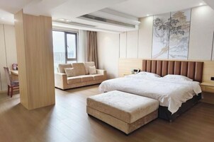 Una habitación de hotel moderna con una cama grande, un sofá, un escritorio y un ventanal amplio.