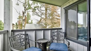 A covered porch with two metal chairs and a small round table. - Sneaky Moose Townhome, 2BR / 2BA (Kenai)