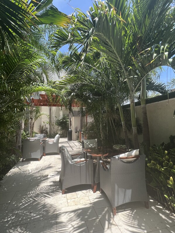 Ein Terrassenbereich im Freien mit Korbmöbeln und Palmen.