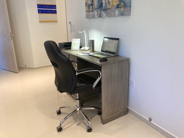 Un bureau moderne avec un ordinateur portable, une lampe de bureau et une chaise.