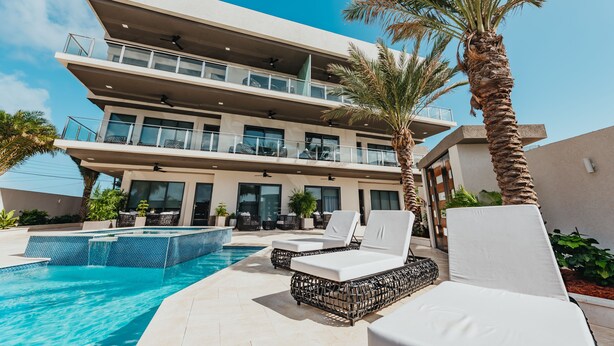Ein modernes Hotel mit Pool, Liegestühlen und Palmen.