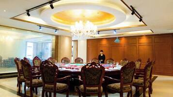 A conference room with a round table, chairs, a chandelier, and a person standing.