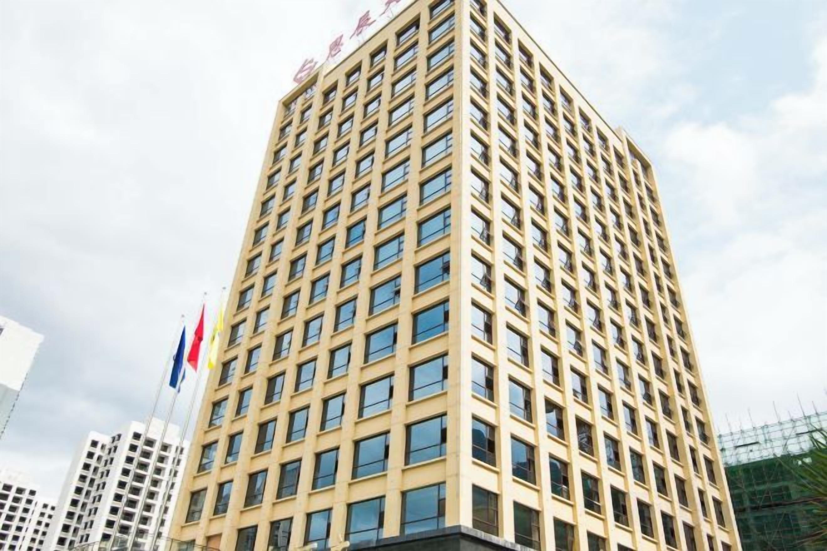 A high-rise building with a grid of windows, likely a hotel or office building, with flags on top.