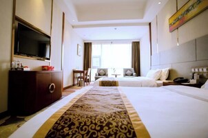Habitación de hotel con dos camas, televisión, escritorio y ventana con cortinas.