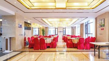 Un salón de banquetes con mesas dispuestas para eventos, una mesa de recepción y una vista despejada de la entrada.