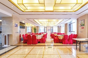 Un salón de banquetes con mesas dispuestas para eventos, una mesa de recepción y una vista despejada de la entrada.