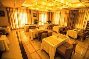 A hotel dining area with multiple tables and chairs, arranged in a spacious layout. - Si Chen Hotel (Yinjiang)