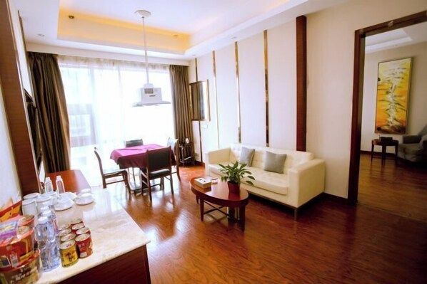 A hotel room with a dining area, a sofa, a coffee table, and a potted plant. - Si Chen Hotel (Yinjiang)