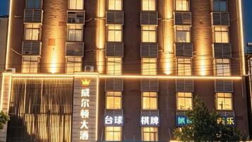 Un hotel de varios pisos, con ventanas iluminadas y un cartel llamativo con caracteres chinos.