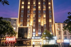 A multi-story hotel with a prominent entrance and illuminated signage. - Wilton Hotel (Xiaochang) (Xiaochang)