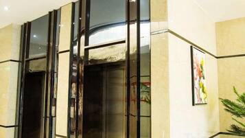 A hotel elevator with glass doors and a handrail.