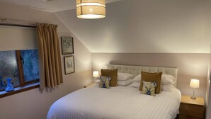 A bedroom with a large bed, two bedside lamps, a window with curtains, and a ceiling light. - Foxglove Cottages (Drymen)