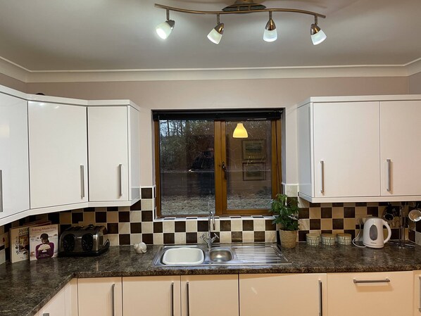 Una cocina con armarios blancos, encimera de granito, un lavabo y una ventana con vistas al exterior.