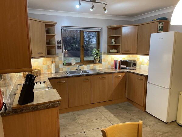 A kitchen with wooden cabinets, a sink, a microwave, and a refrigerator.
