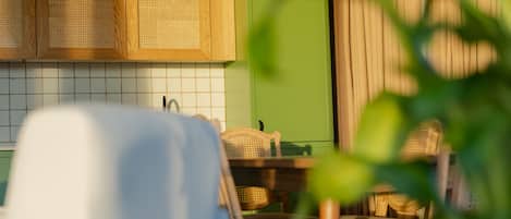 A kitchen with wooden cabinets, a green wall, and a wicker chair.