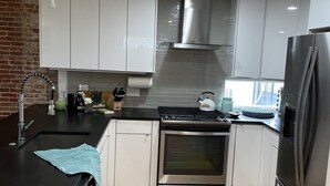 A modern kitchen with white cabinets, stainless steel appliances, and a black countertop. - Entire condo center of downtown Newburyport (Newburyport)