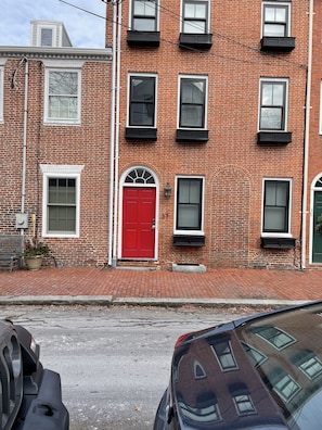 Un bâtiment en briques rouges, doté de nombreuses fenêtres et d’une porte rouge.