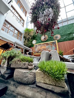A modern indoor atrium with a high ceiling, large windows, and a central hanging floral arrangement. - Intiwatana Hotel Boutique (Cusco)