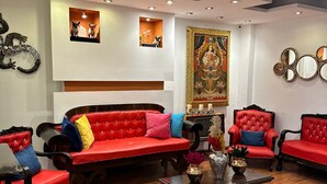 A spacious living area with a red sofa set, a coffee table, and a large decorative painting on the wall. - Intiwatana Hotel Boutique (Cusco)