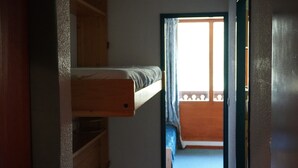 A narrow hallway leading to a balcony with a wooden bunk bed. - Studio terrace with beautiful view and direct access to all hiking trails; sleeps 4 (Modane)