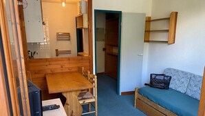 A compact room with a wooden dining table, a sofa, and a television. - Studio terrace with beautiful view and direct access to all hiking trails; sleeps 4 (Modane)