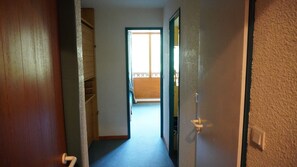 Leading to a balcony with an outdoor view, this hallway features a door on each side and a carpeted floor.