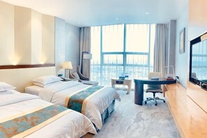Une chambre d’hôtel avec deux lits, un bureau, une chaise, une télévision et une grande fenêtre.