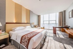 A modern hotel room with a large bed, a desk, and a view of the city. - Jinya Hotel (Xixiang)