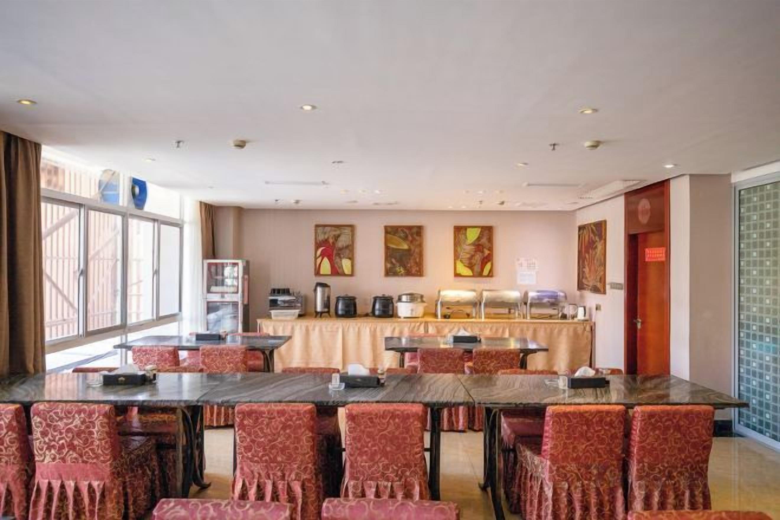 A conference room with multiple tables and chairs, a buffet setup, and artwork on the walls.