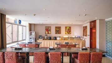 A conference room with multiple tables and chairs, a buffet setup, and artwork on the walls.