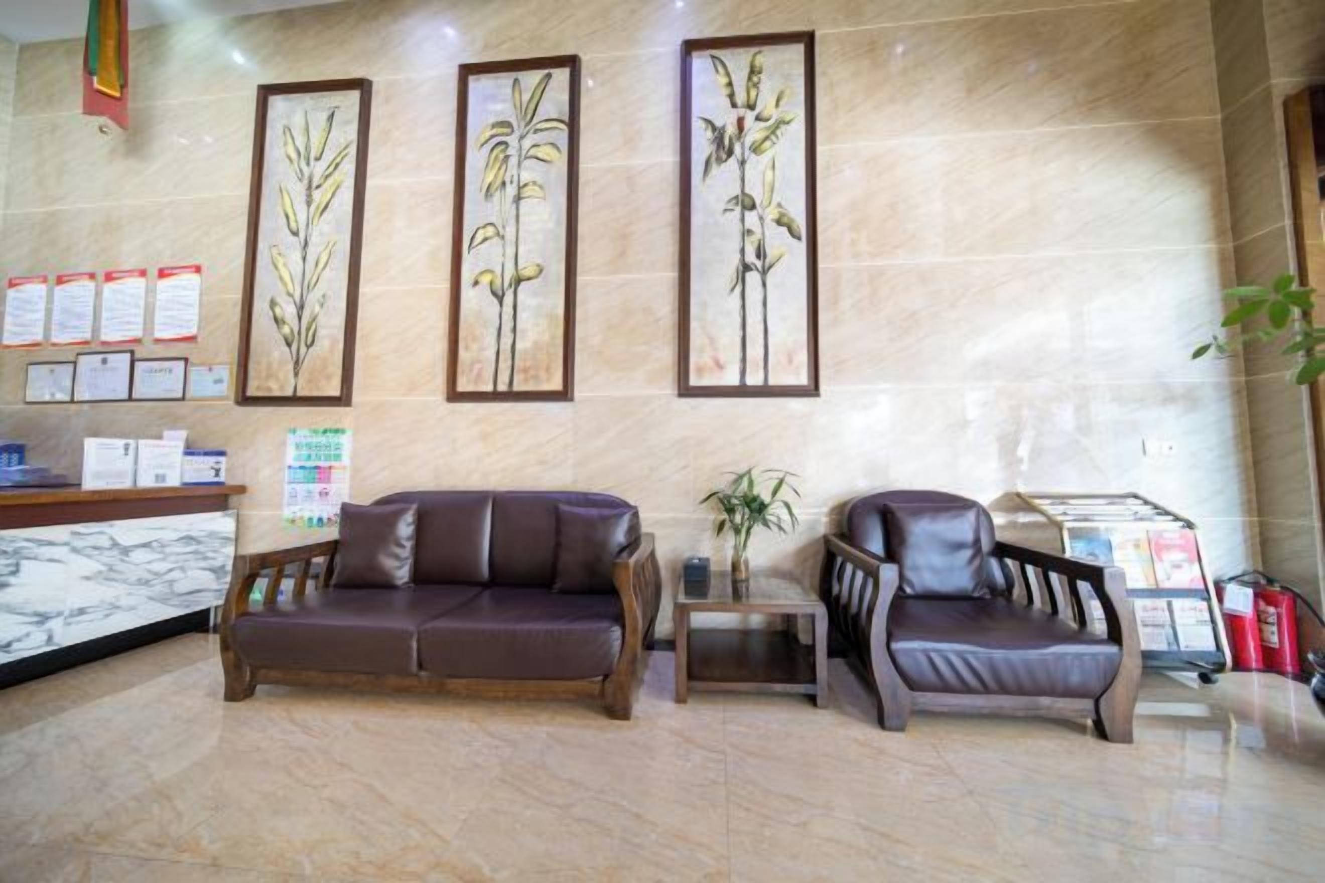 A reception area with a marble floor, two leather sofas, framed botanical artwork, a reception desk, and informational posters.