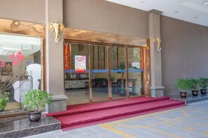 A hotel entrance with a red carpet, glass doors, and potted plants. - Jensland Hotel (Fuqing)