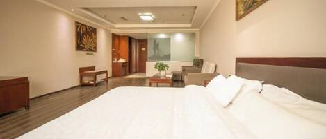 A hotel room with a large bed, a desk, a chair, a sofa, and a painting on the wall.