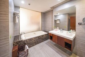 A modern bathroom with a large bathtub, two sinks, and a mirror.