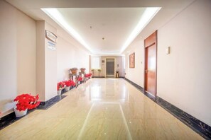A hotel corridor with a polished floor, potted plants, and a door at the end. - Jensland Hotel (Fuqing)